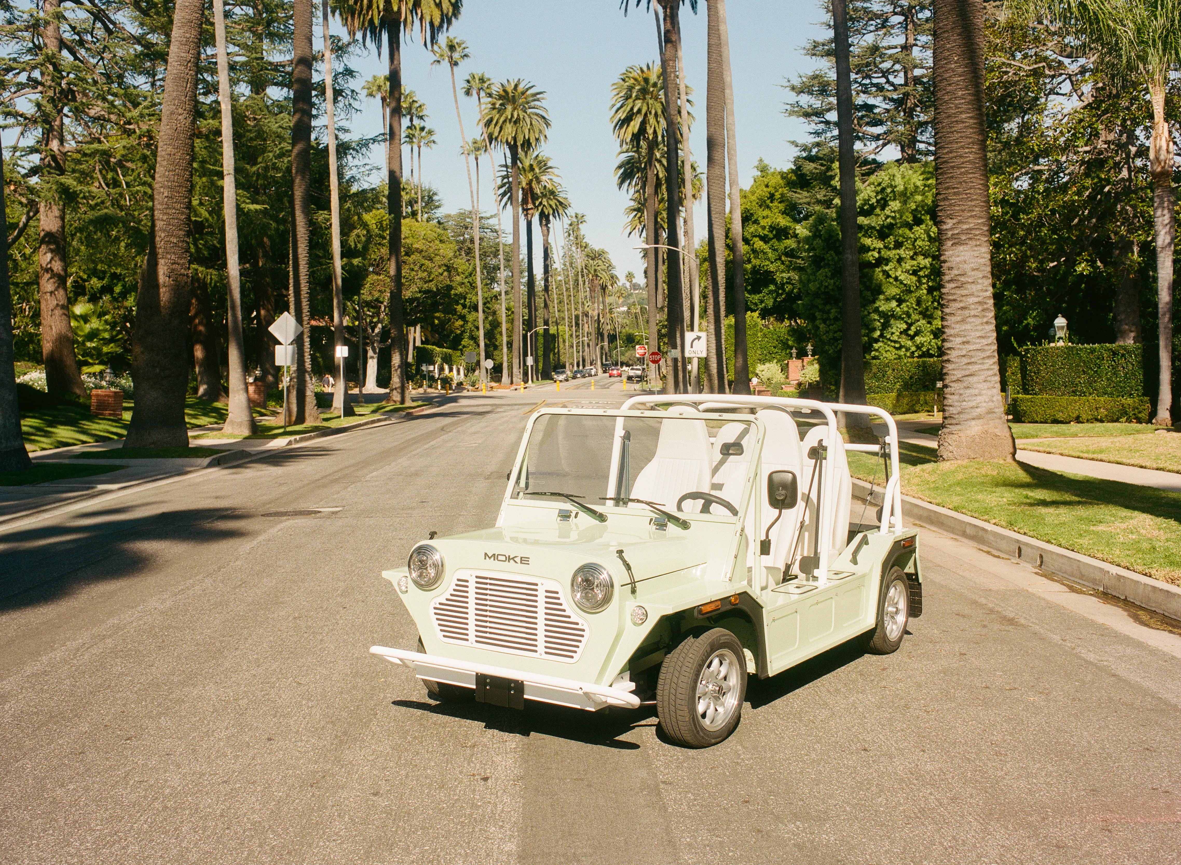 White Moke cruising down a palm-tree-lined boulevard