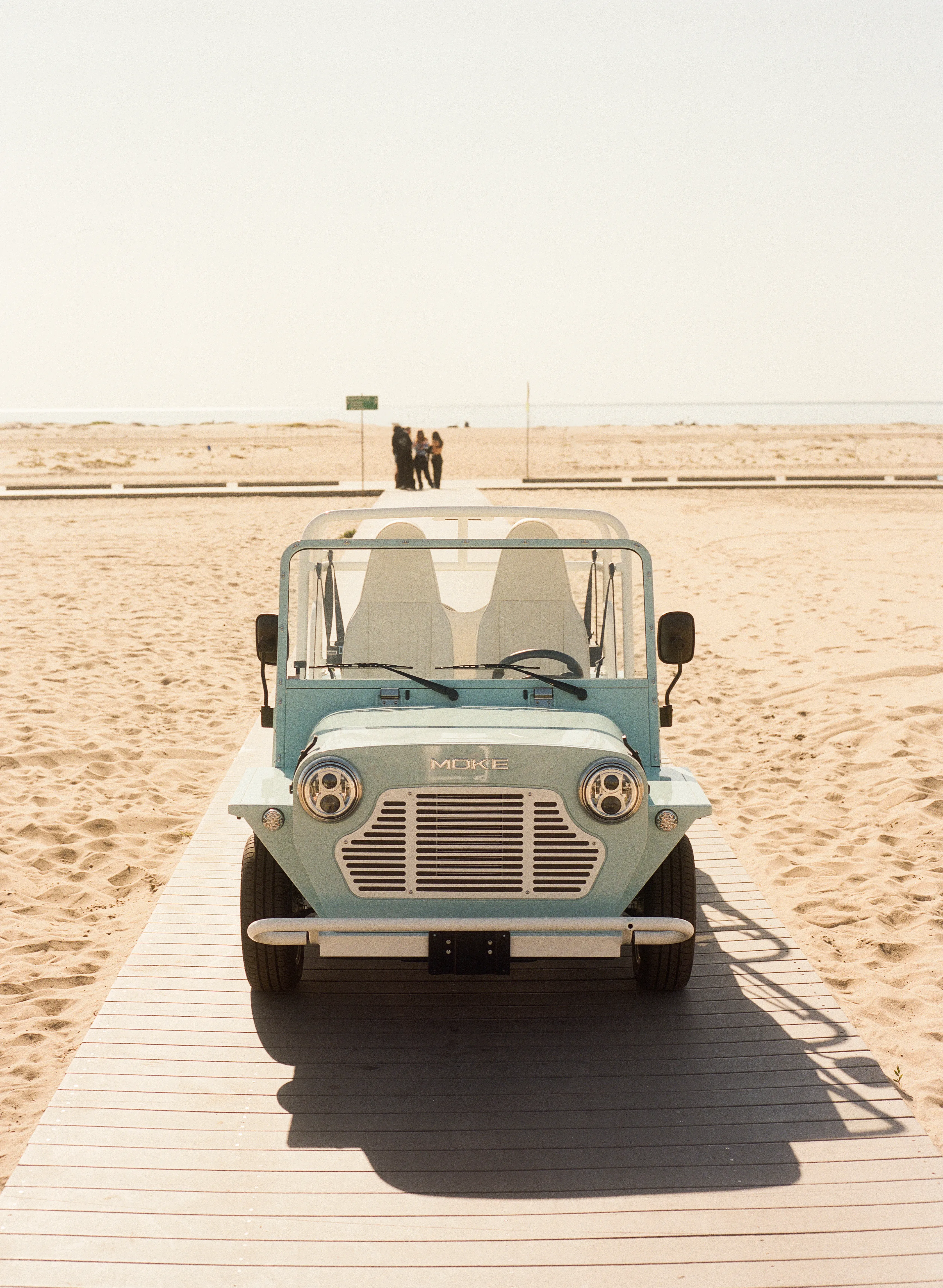 Moke driving along a coastal road at golden hour