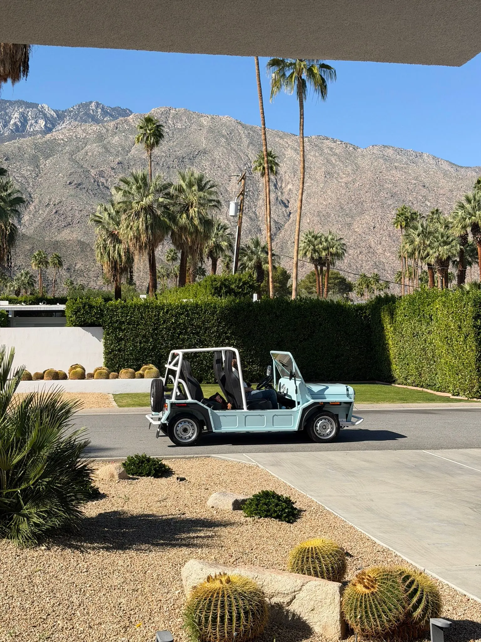 Moke EV driving on a desert road with Sedona red rock formations in the background