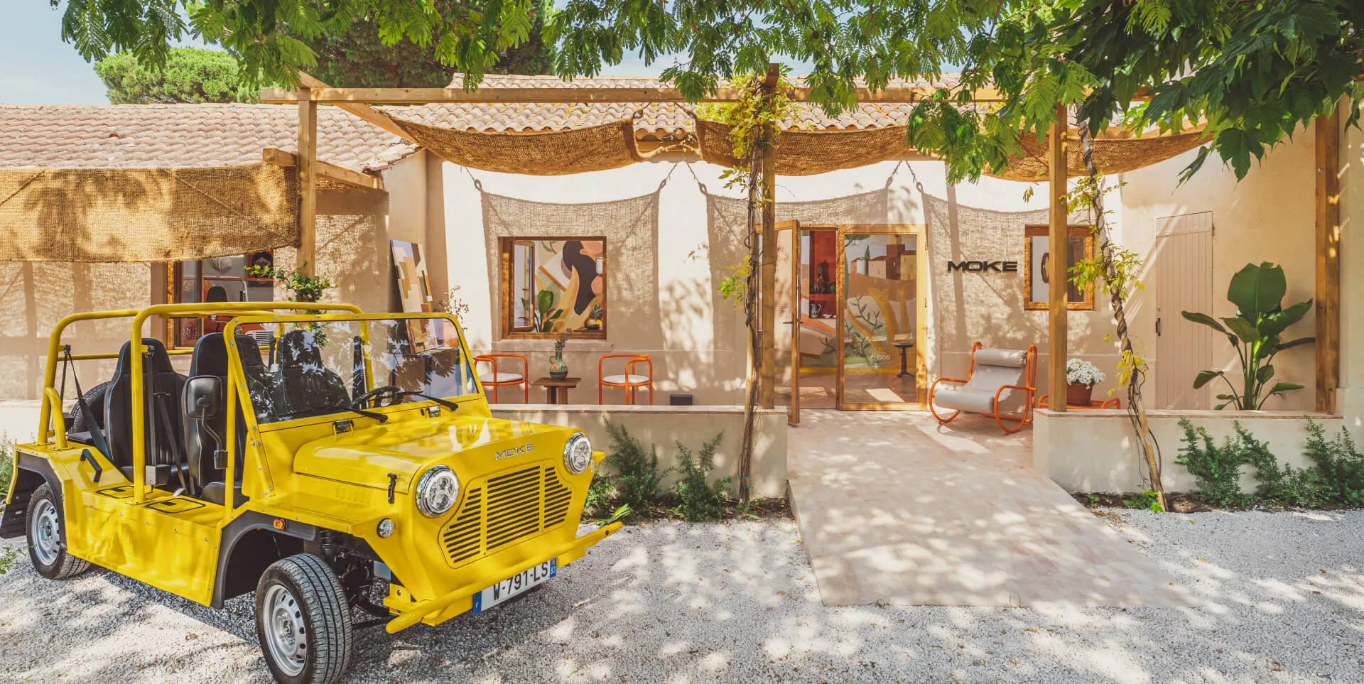 Authentic Moke EV on a palm-lined South Florida road with art deco architecture