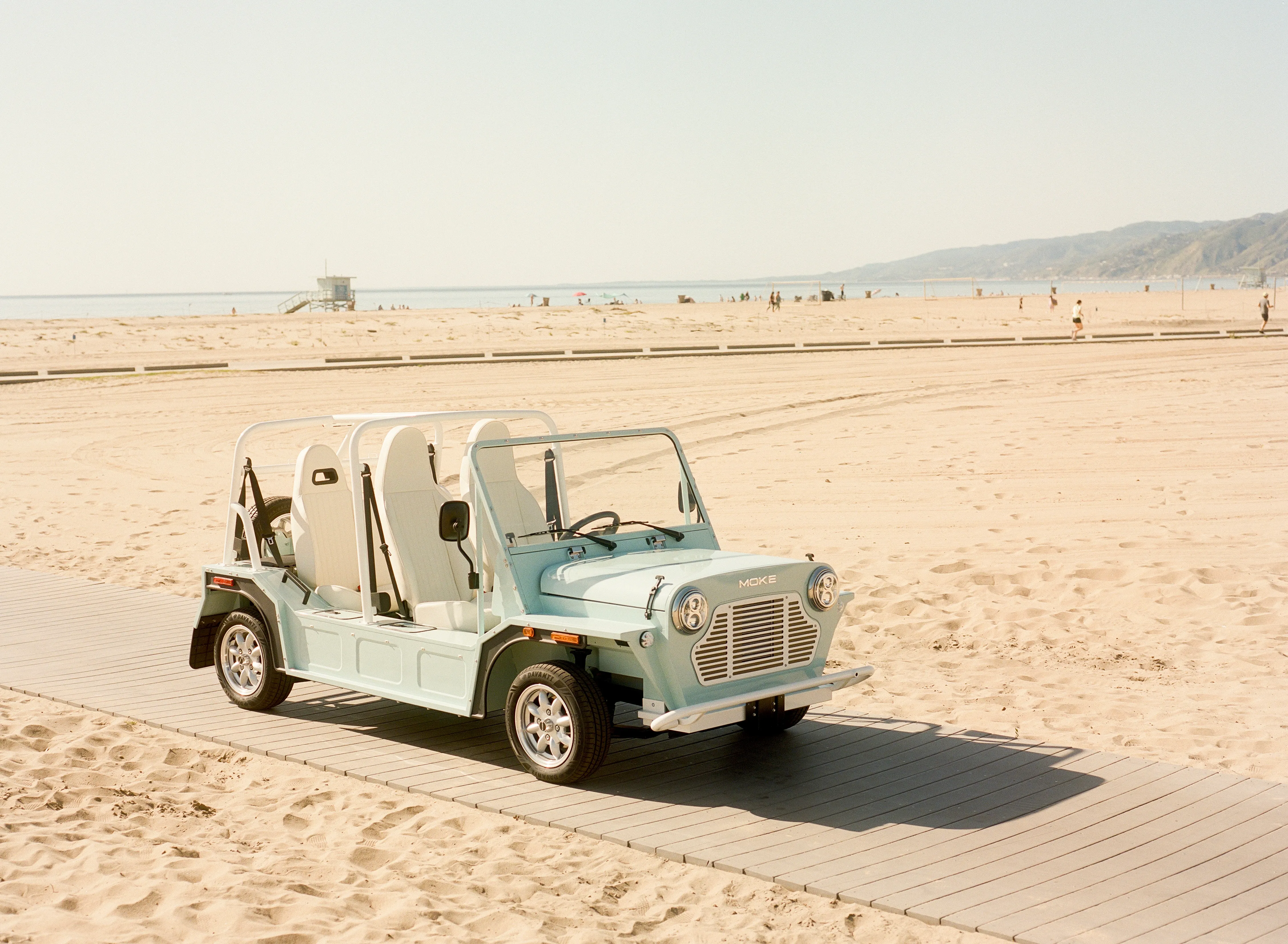 Moke vehicle on a sun-drenched beach boardwalk