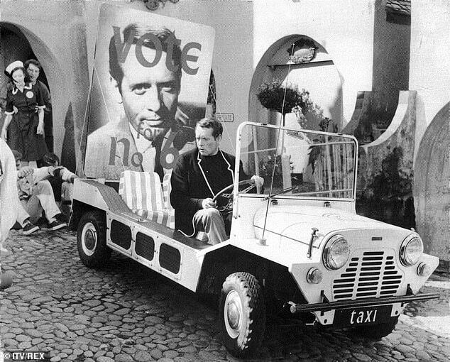 Patrick McGoohan sits in a white Mini Moke marked 'taxi' in a scene from The Prisoner TV series